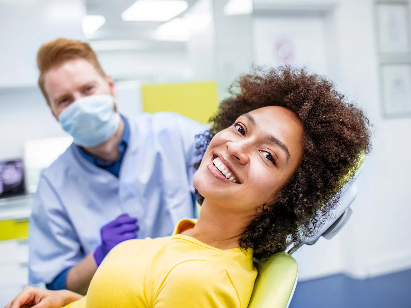 Ein Frau beim Zahnarzt zeigt ein lückenloses Lächeln