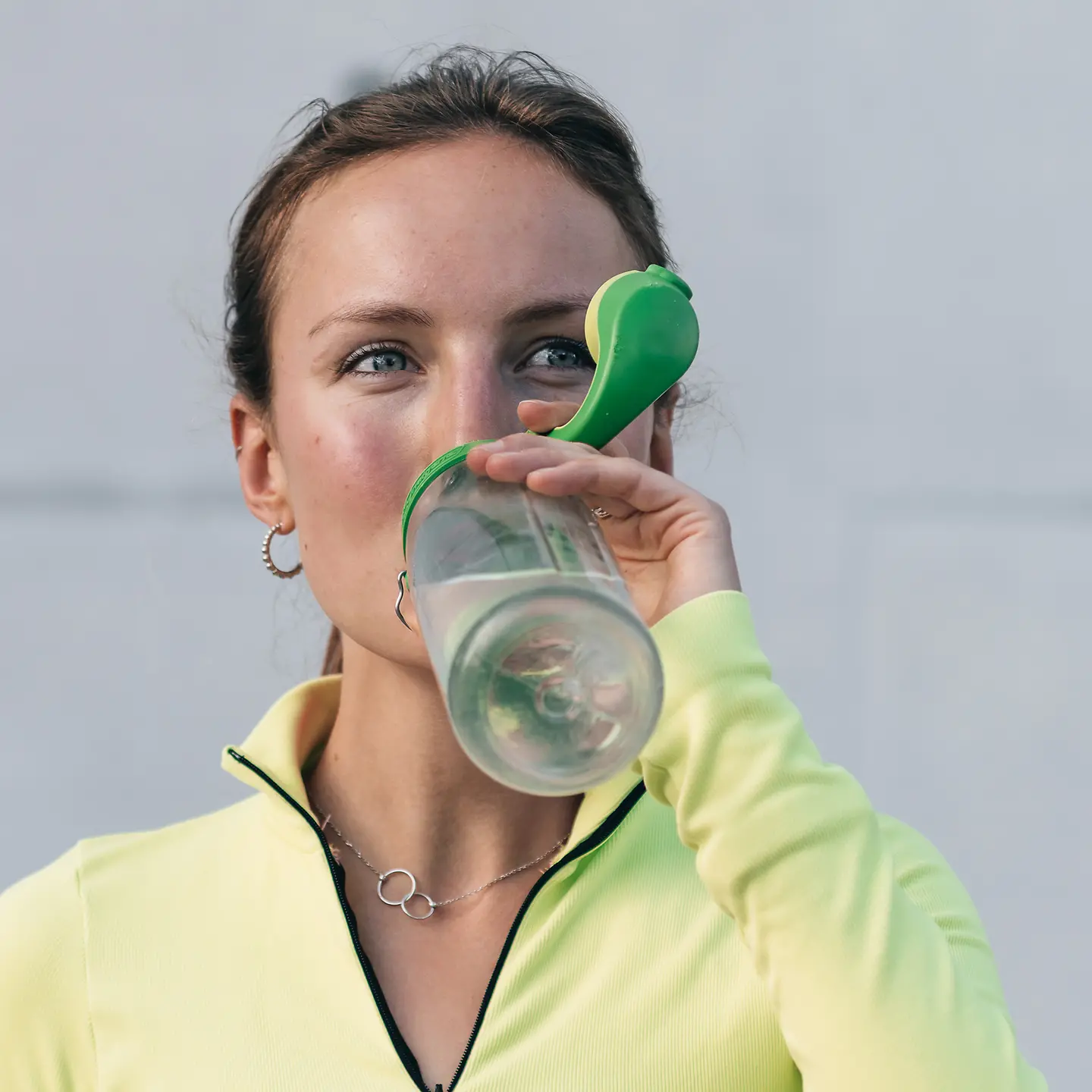 Porträt einer Frau, die nach dem Sport aus einer Plastikflasche trinkt