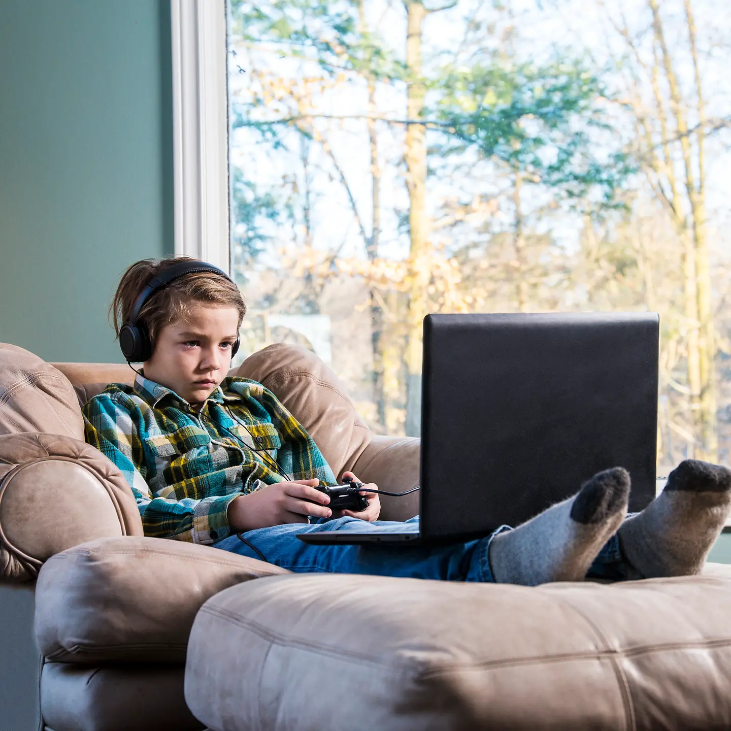 Ein Junge sitzt auf dem Sofa und spielt ein Computerspiel.