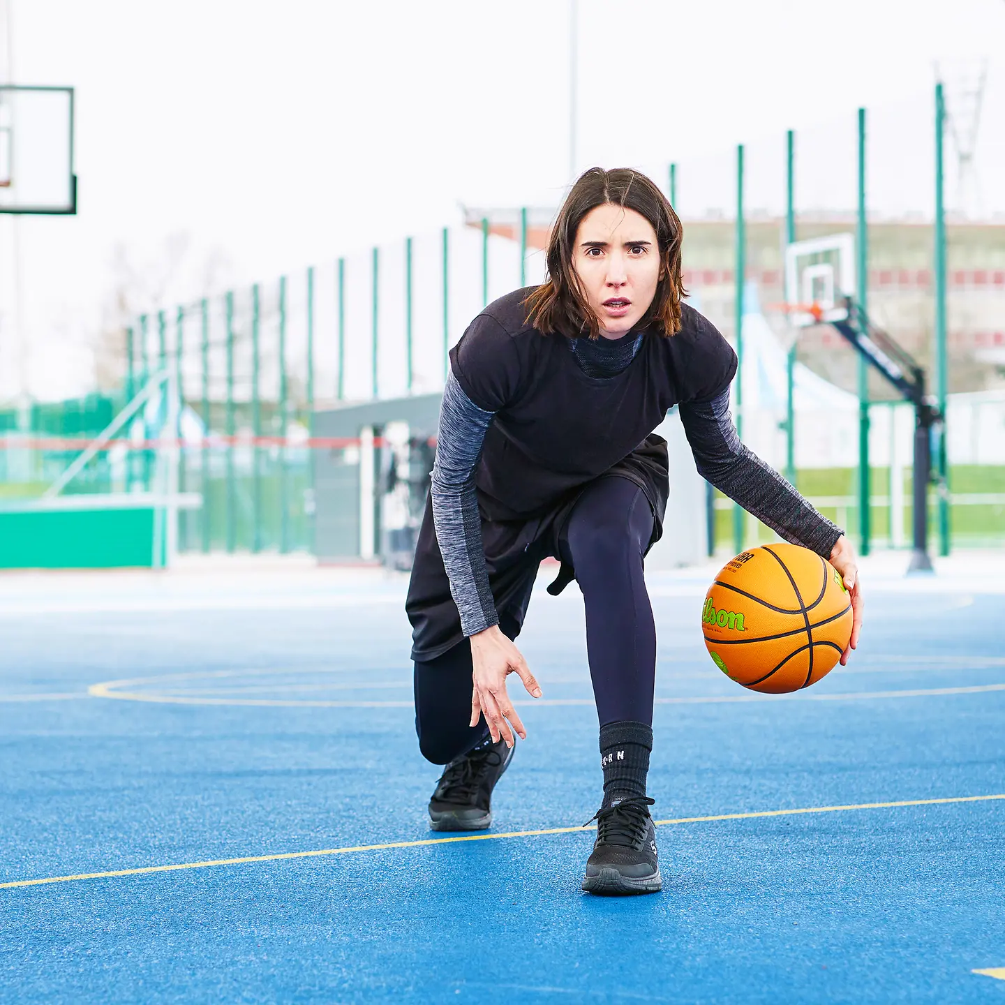 Carolina bewegt sich dribbelt mit einem Basketball in der Hand über den Basketballplatz.