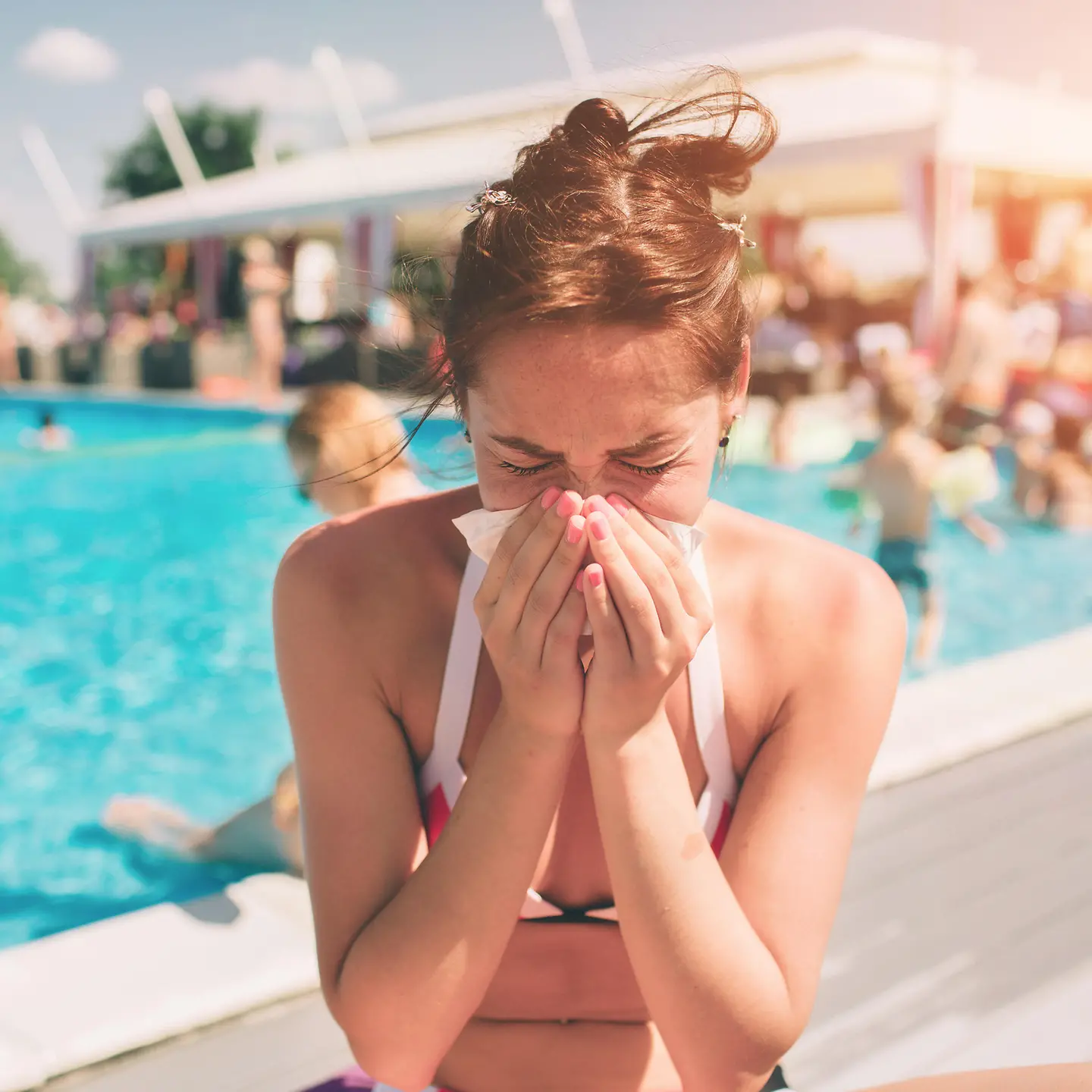 Das Bild zeigt eine Frau, die sich im Freibad ihre Nase putzt.