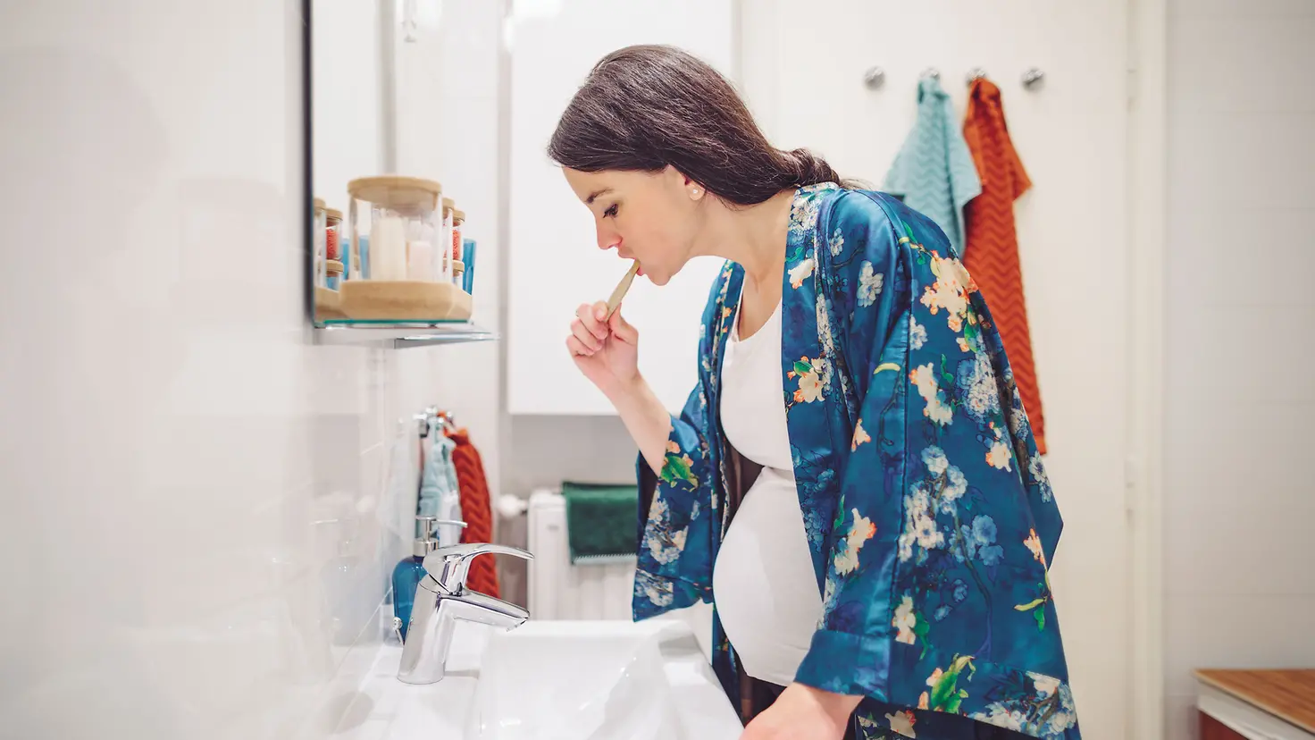 Eine schwangere junge Frau um die 34. Schwangerschaftswoche putzt sich die Zähne