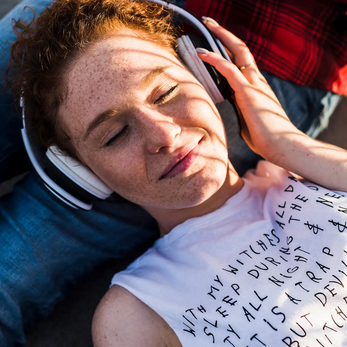 Eine Frau liegt mit Kopfhörern auf dem Boden und testet die Wirkung von binauralen Beats.