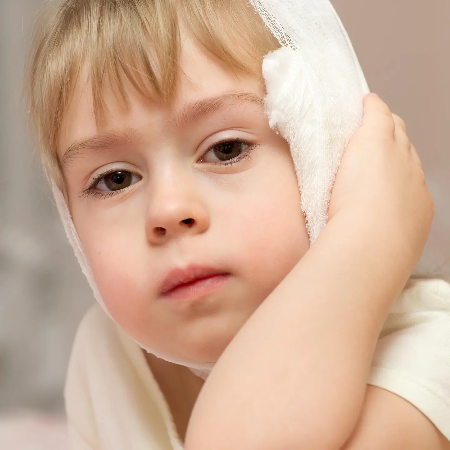 Zu sehen ist ein Kind mit einem Verband am Ohr