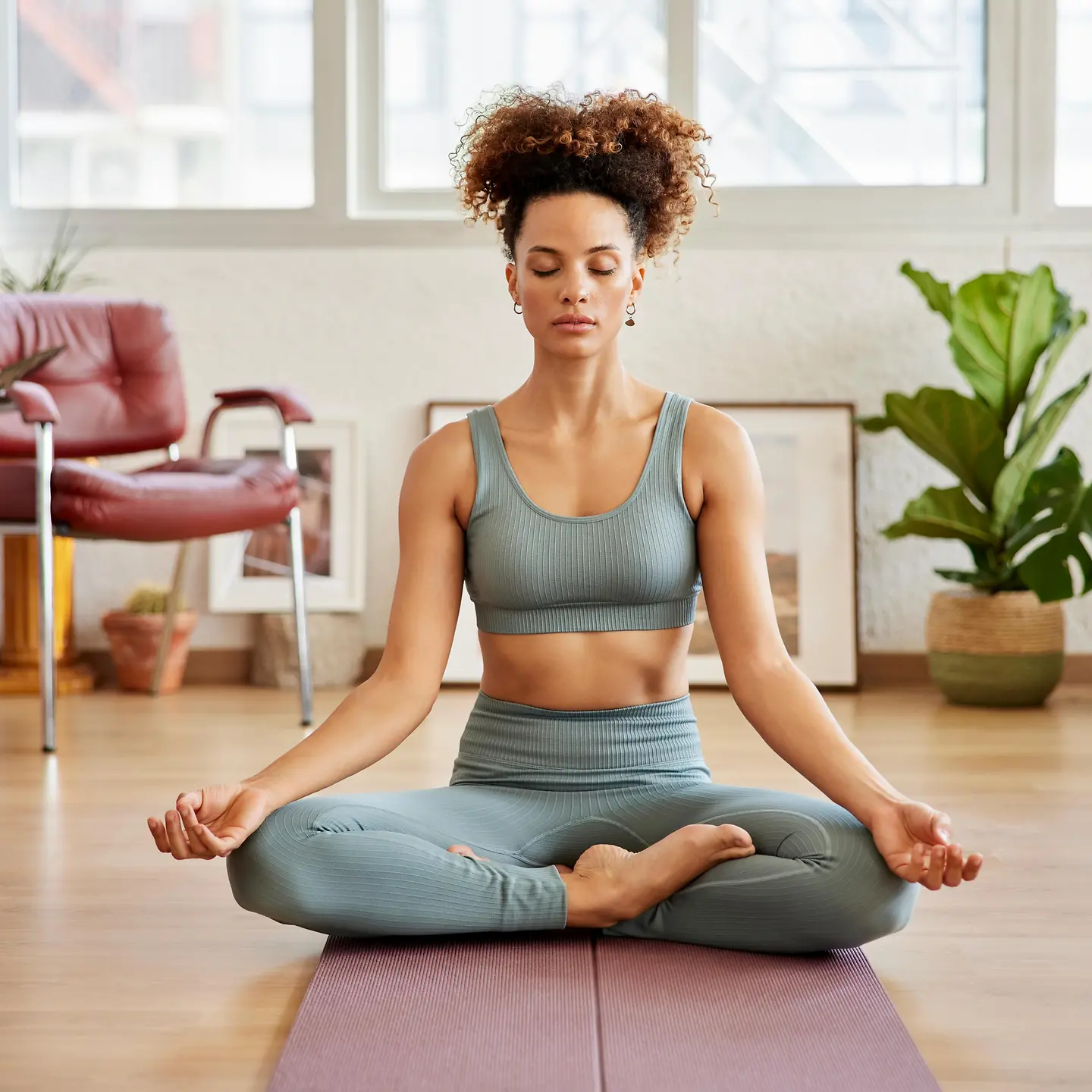 Eine junge Frau sitzt auf einer Yogamatte und macht Atemübungen