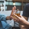 Das Bild zeigt eine Hand, die ein Glas Alkohol ablehnt.