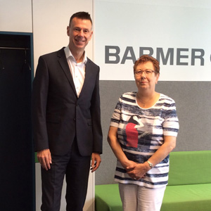 Silvia Altmannsberger und Thorsten Hinkel stehen in einem Barmer-Büro