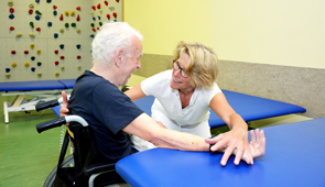 Physio-Therapeutin behandelt einen Rollstuhlfahrer