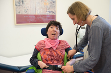 Eine Ärztin versorgt eine Person im Rollstuhl