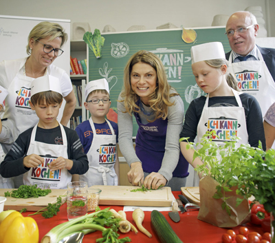 Staatsministerin Klepsch, Sarah Wiener, Paul-Friedrich Loose kochen mit Kindern aus der 54. Grundschule Leipzig