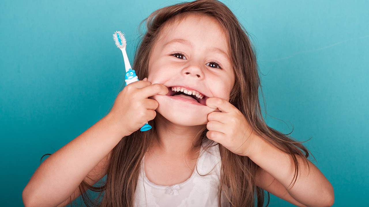 Ein kleines Mädchen schneidet beim Zähneputzen eine Grimasse.