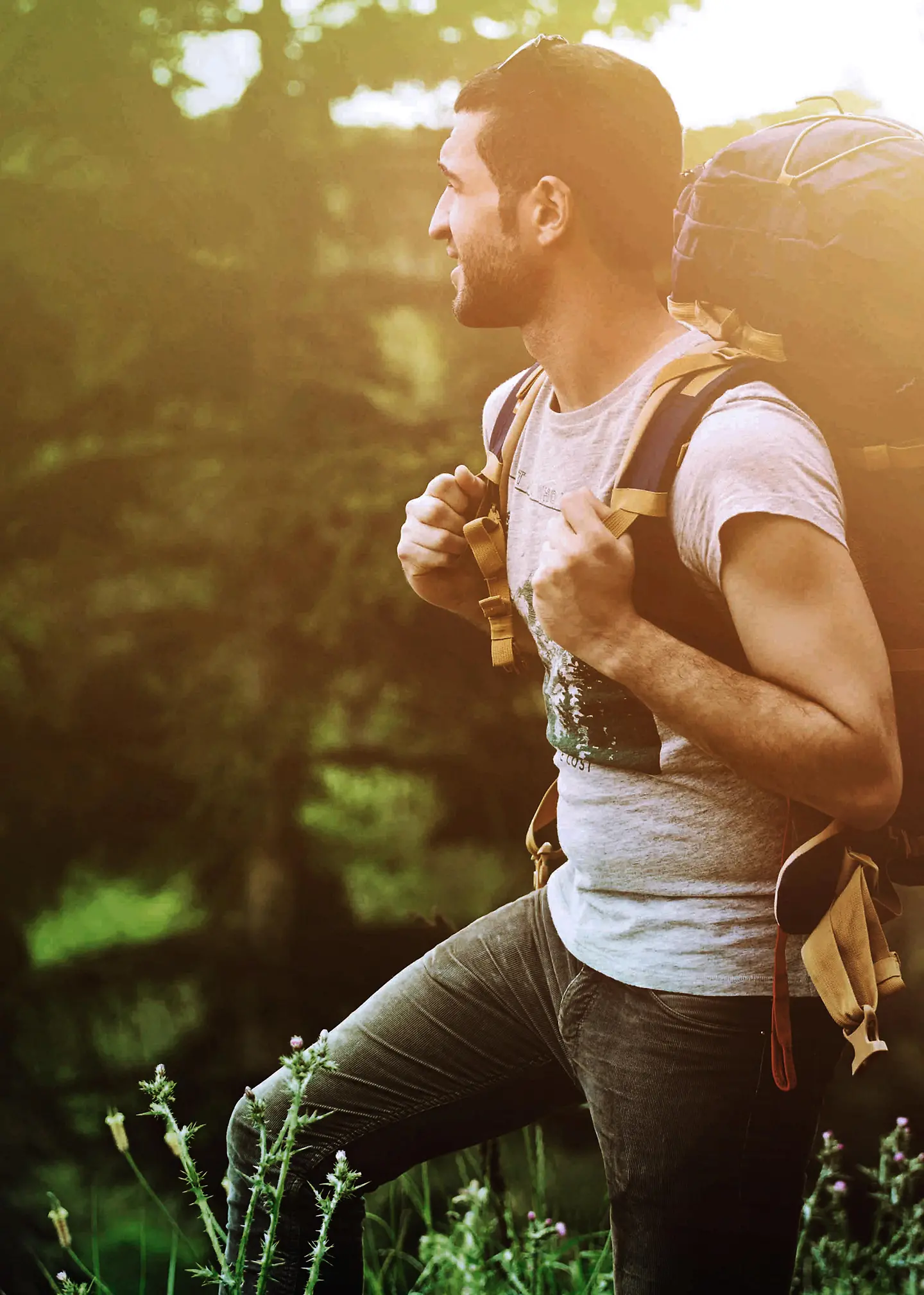 Ein junger Mann mit Rucksack geht durch einen Wald.