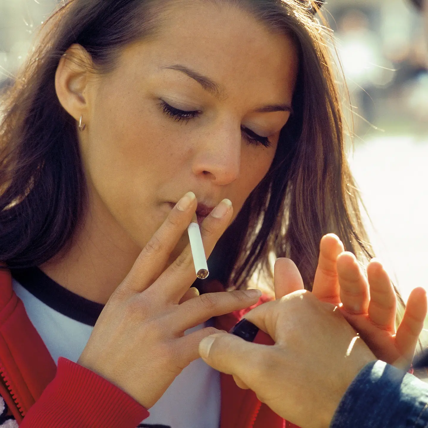 Eine junge Frau lässt sich Feuer für ihre Zigarette geben