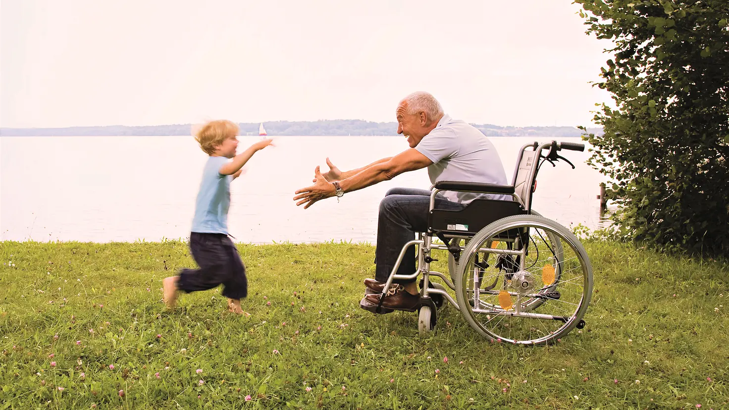 Ein Enkel läuft zu seinem Opa im Rollstuhl