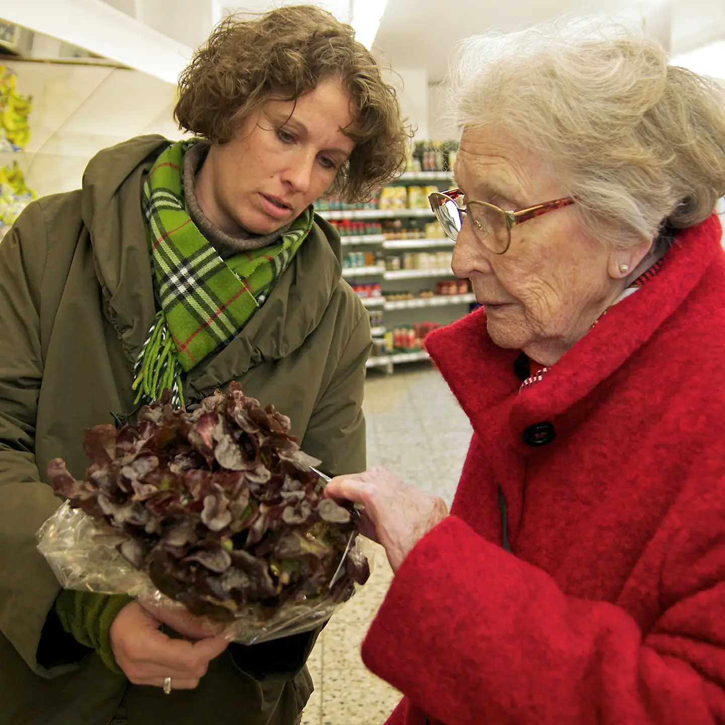 Zwei Frauen schauen sich beim Einkaufen einen Salatkopf an