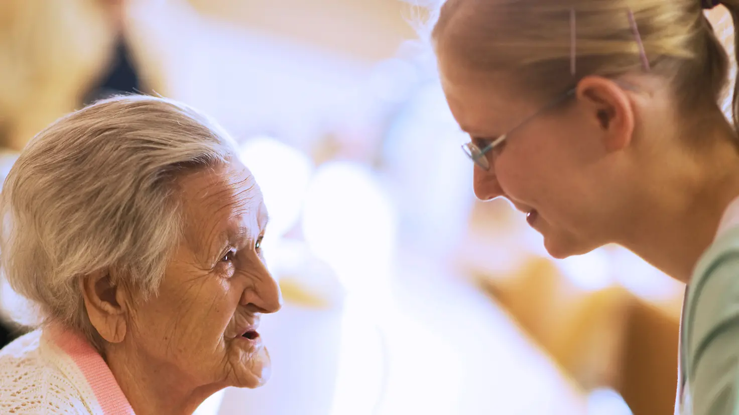 Eine Seniorin spricht mit einer Pflegekraft