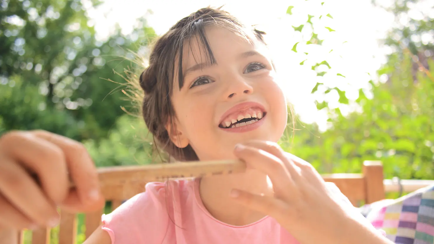 Ein lächelndes Mädchen sitzt auf einer Gartenbank