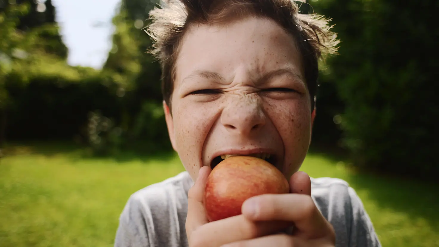 Ein Junge beißt in einen Apfel