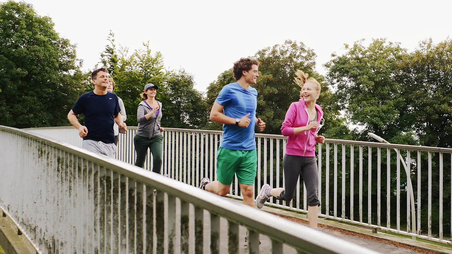 Vier Jogger laufen über eine Brücke.