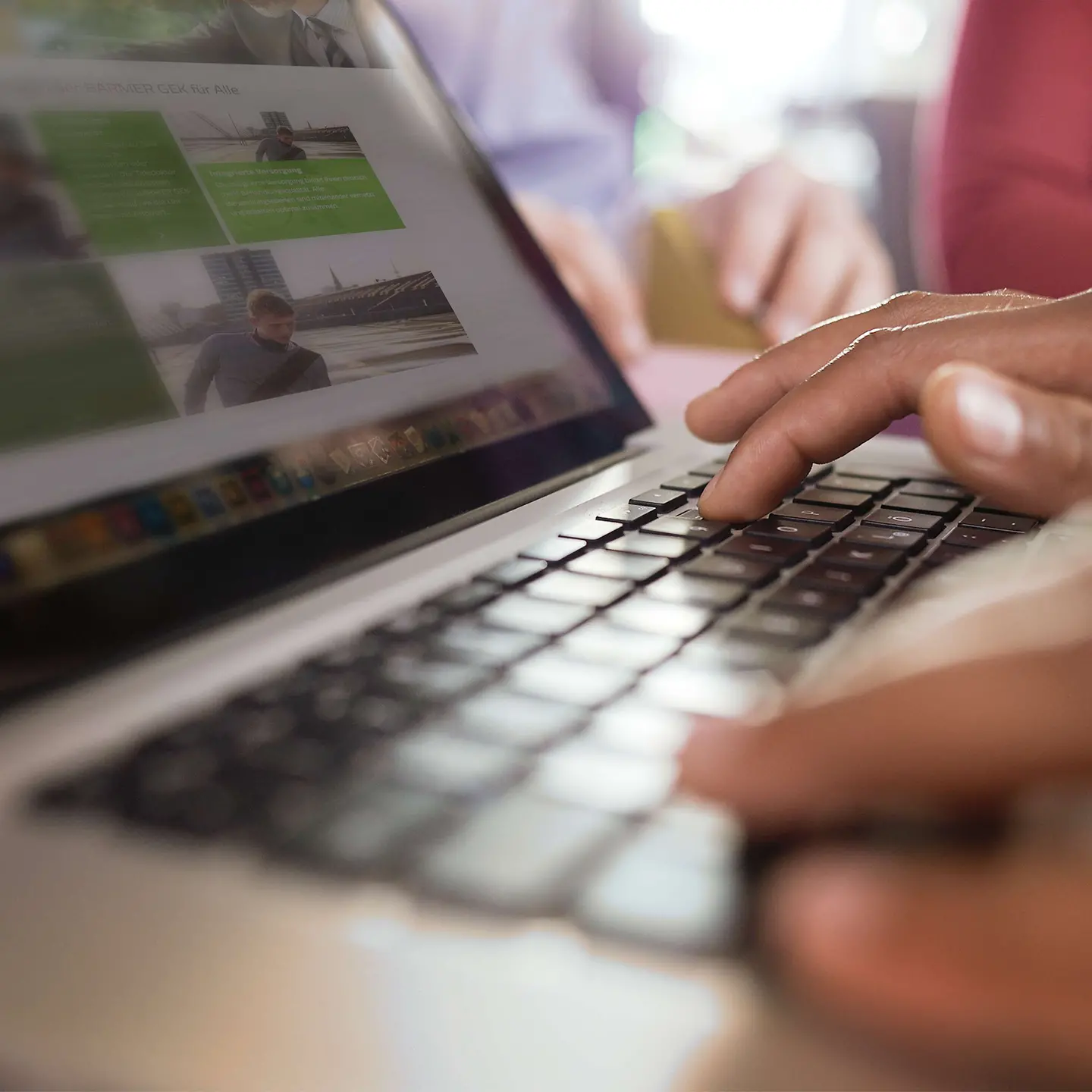 Hände tippen auf einer Notebook-Tastatur. Auf dem Bildschirm ist die BARMER Webseite zu sehen.