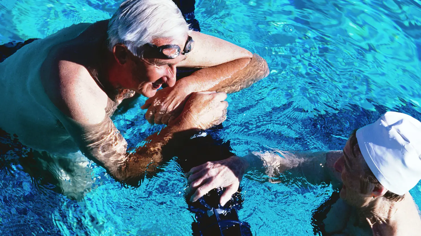 Zwei ältere Menschen unterhalten sich im Schwimmbecken