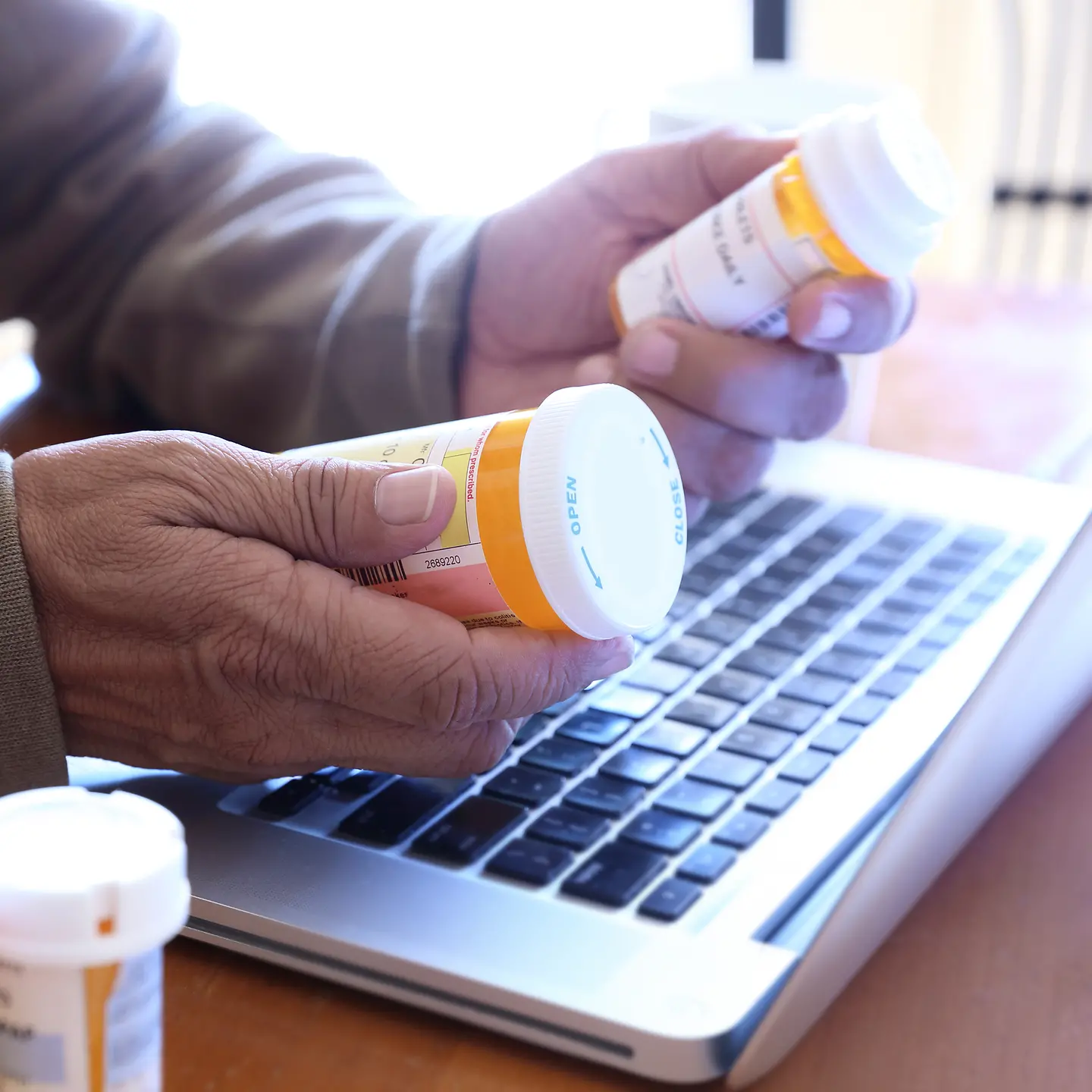 Eine ältere Person hält zwei Tablettendosen in den Händen