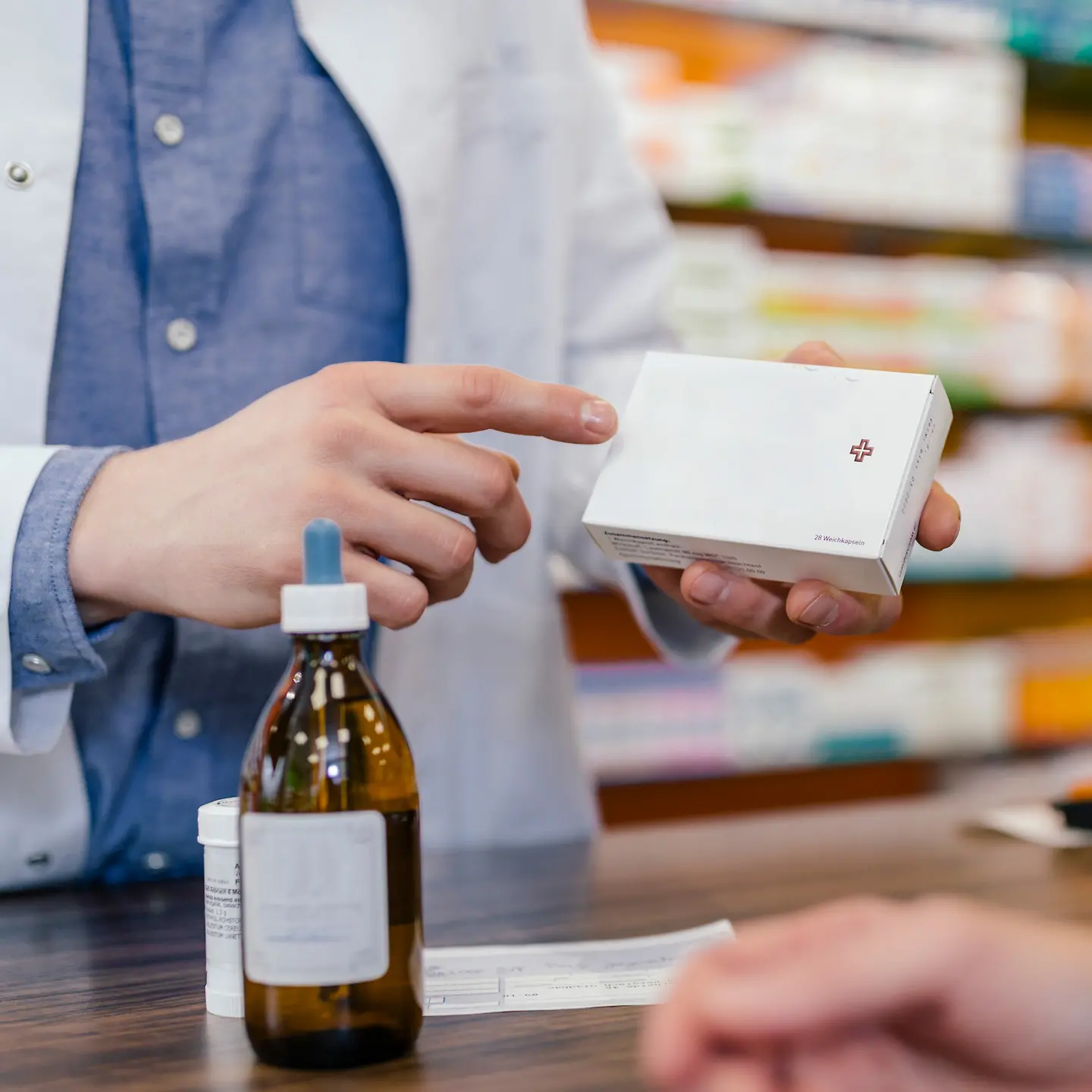 Ein Apotheker zeigt mit seinem Finger auf eine Tablettenverpackung