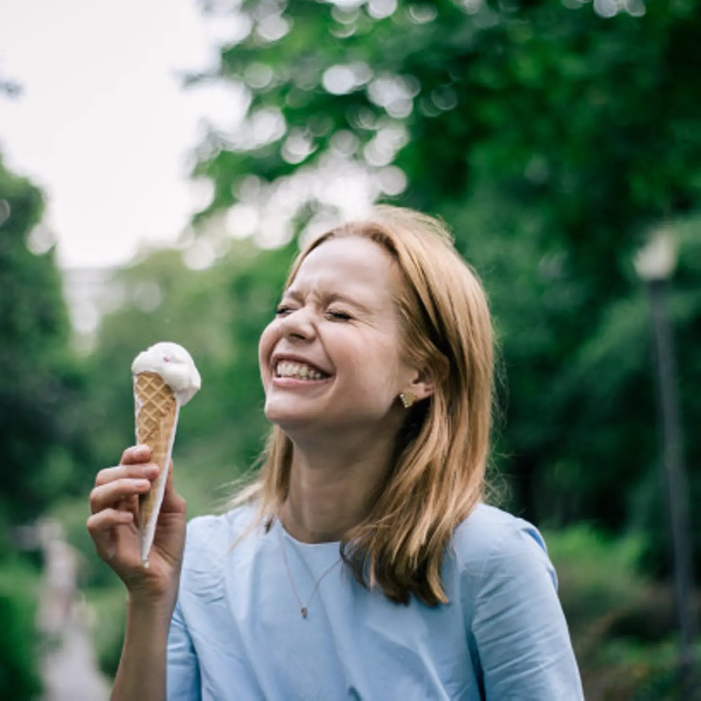 Foodbloggerin Rebecca Hoffmann hält eine tropfende Eistüte in der Hand und lacht.