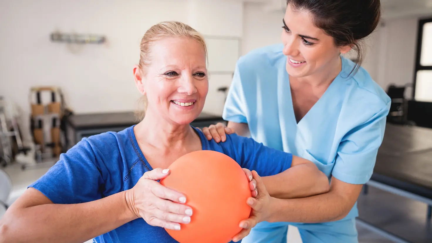 Eine Therapeutin mit einer Patientin während einer Ball-Trainingseinheit