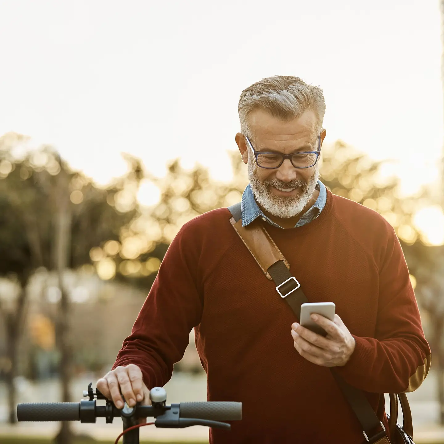 Ein Mann hält sein Fahrrad fest und schaut aufs Handy. 