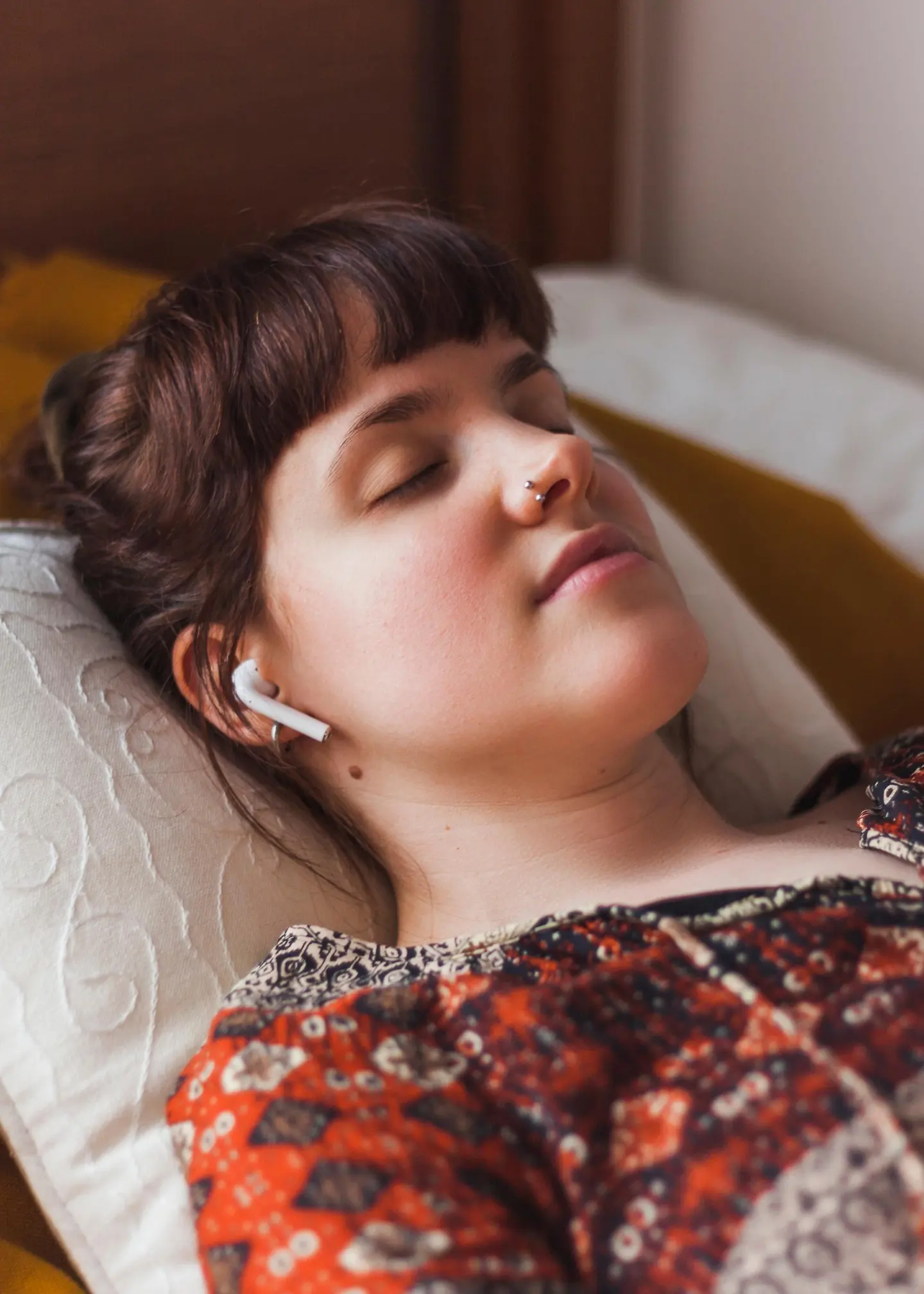 Eine Frau liegt mit Kopfhörern im Ohr schlafend im Bett