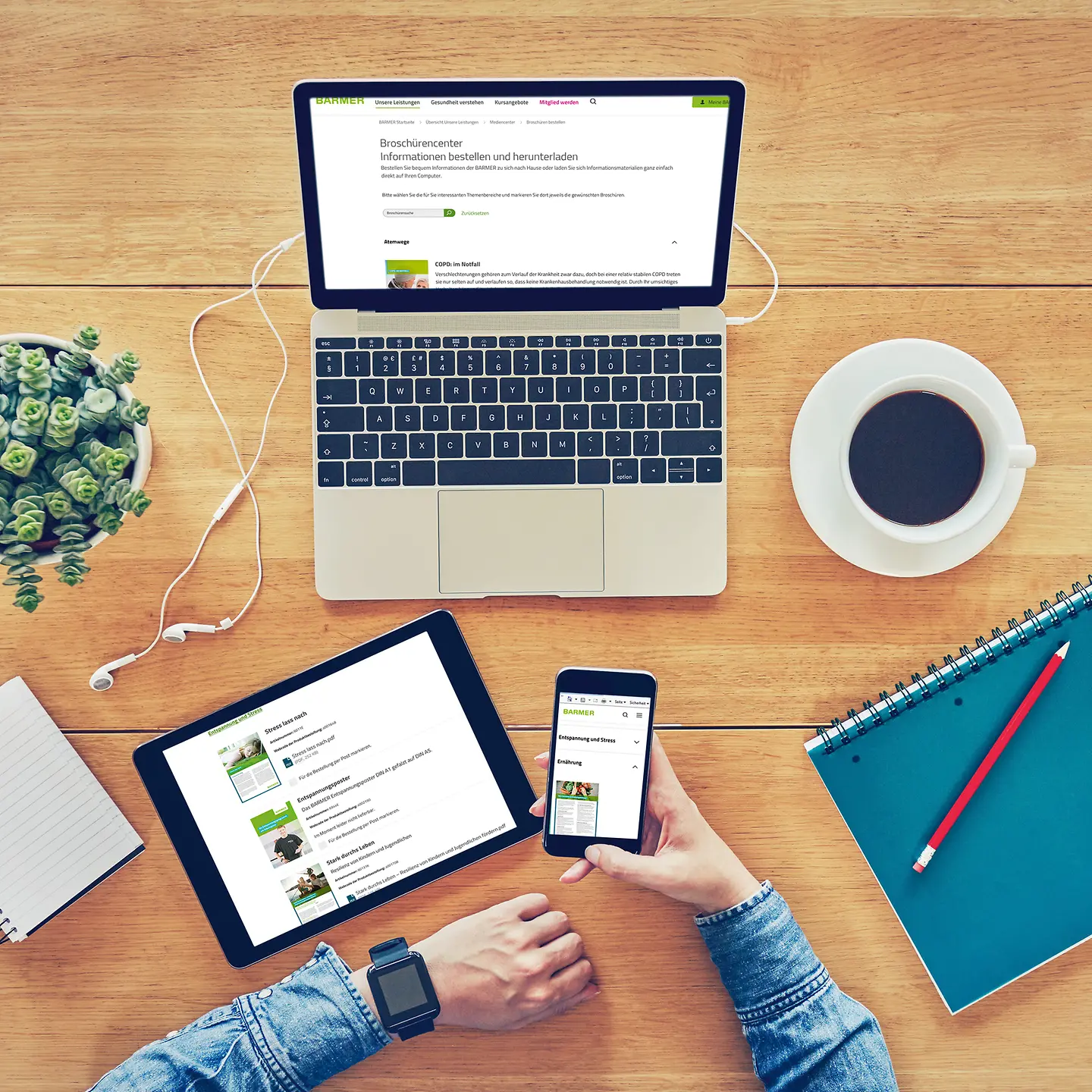 Ein Laptop, ein Tablet und ein Smartphone liegen auf einem Schreibtisch