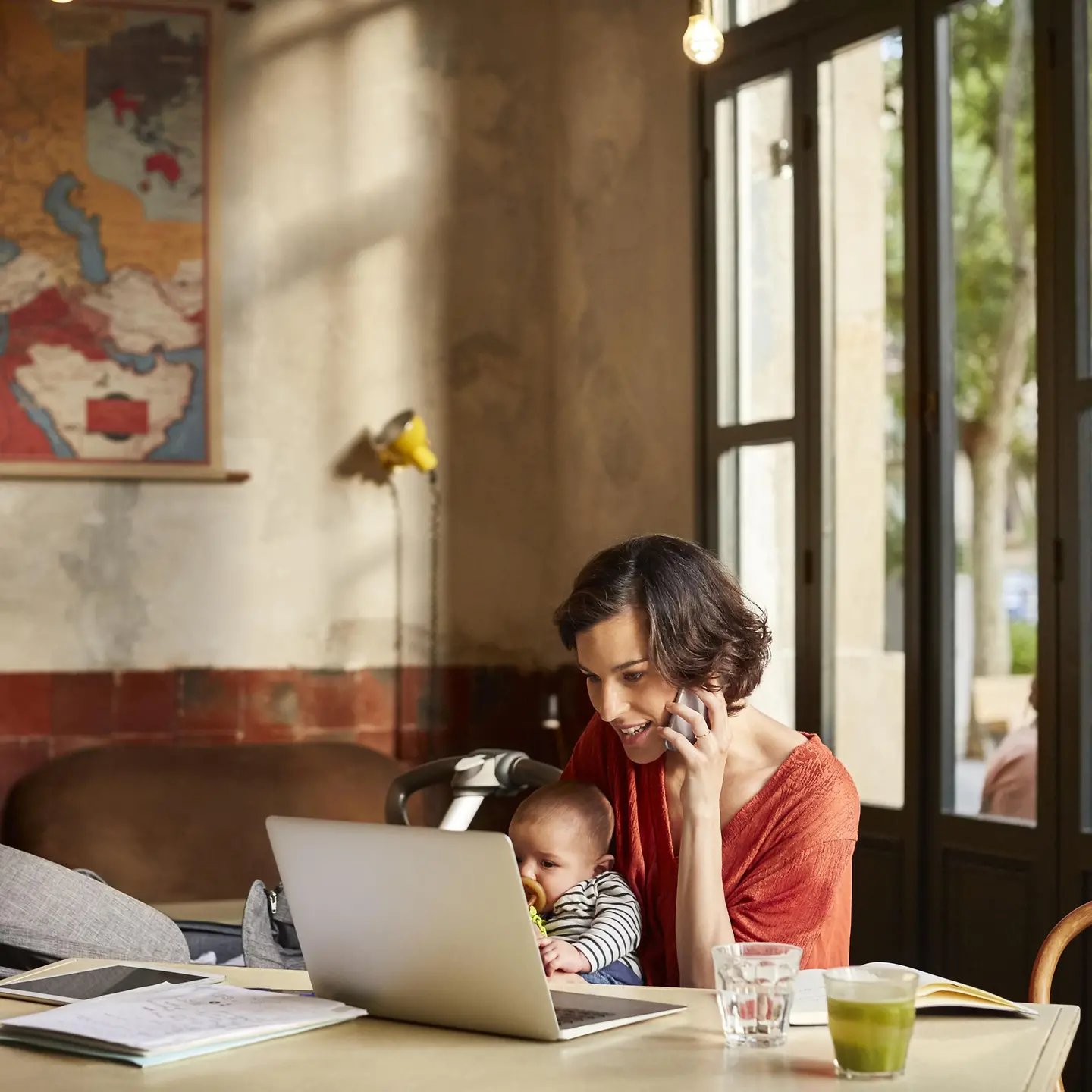 Eine Frau mit Laptop und Kind in einem Café.