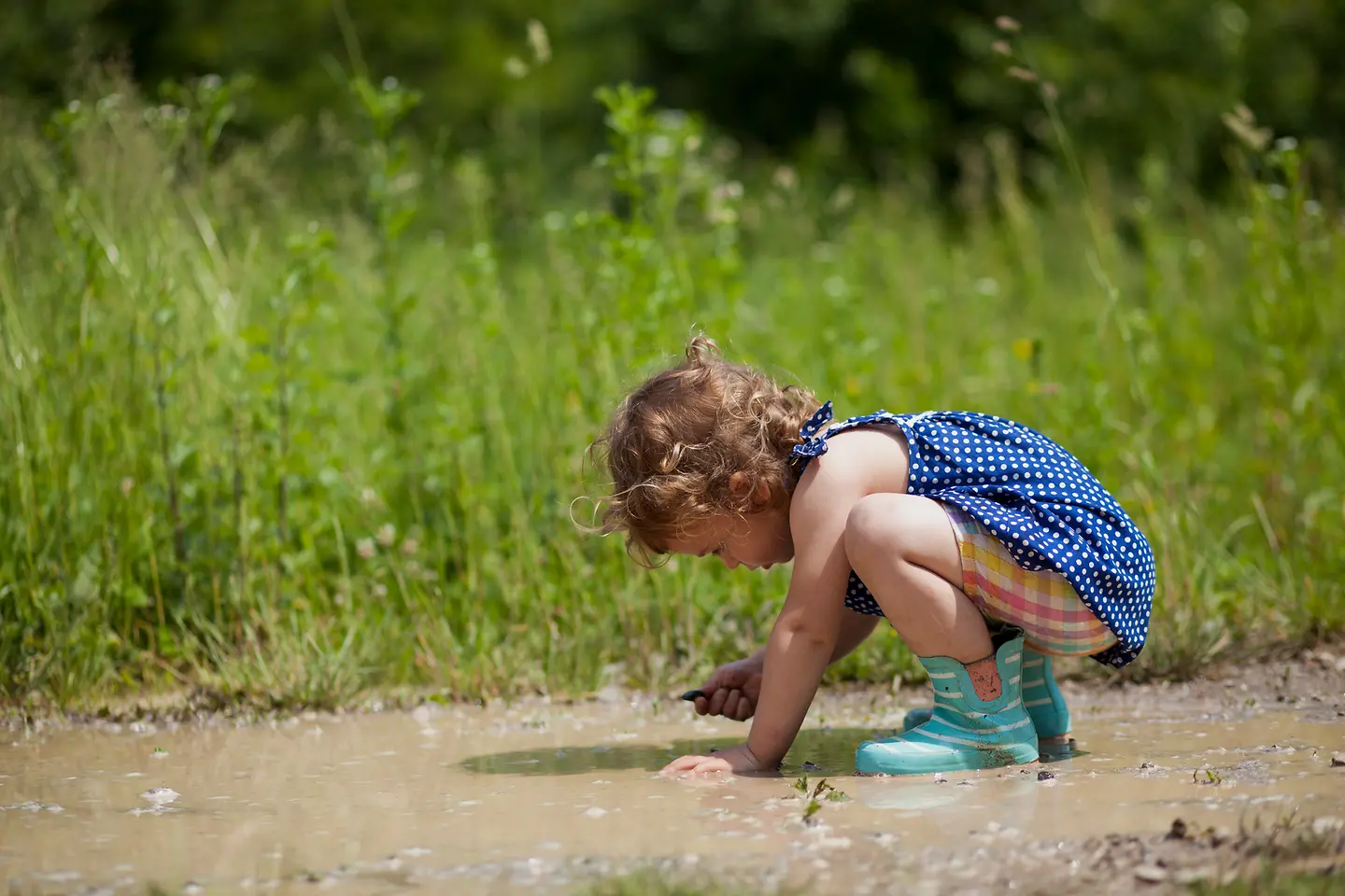 Ein kleines Mädchen spielt in einer Pfütze