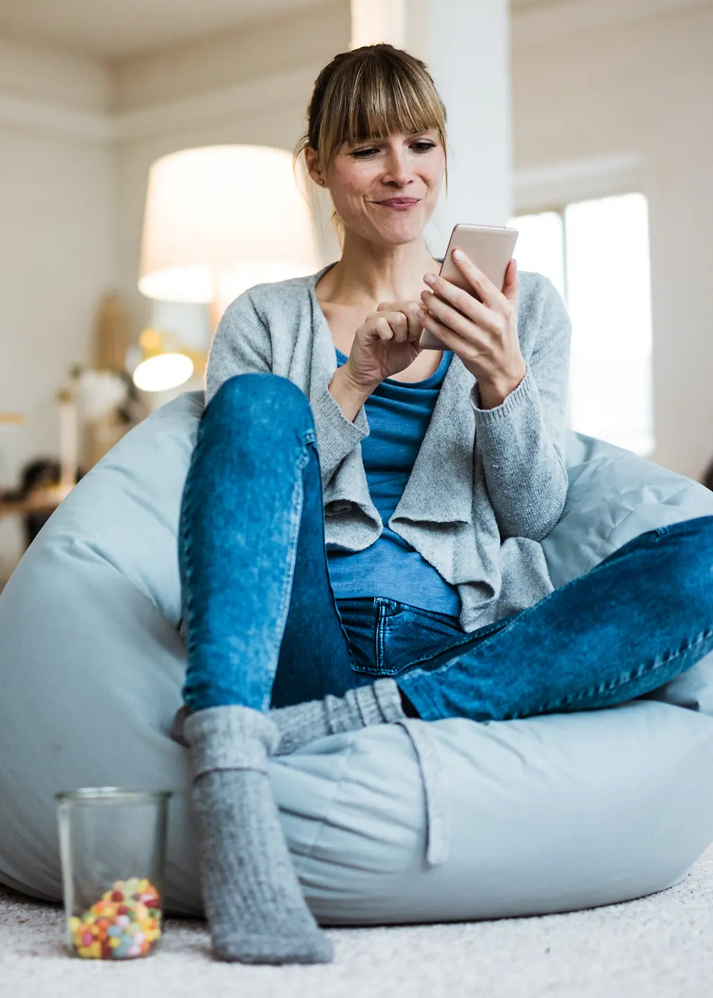 Frau auf einem Sitzsack schaut auf ihr Smartphone