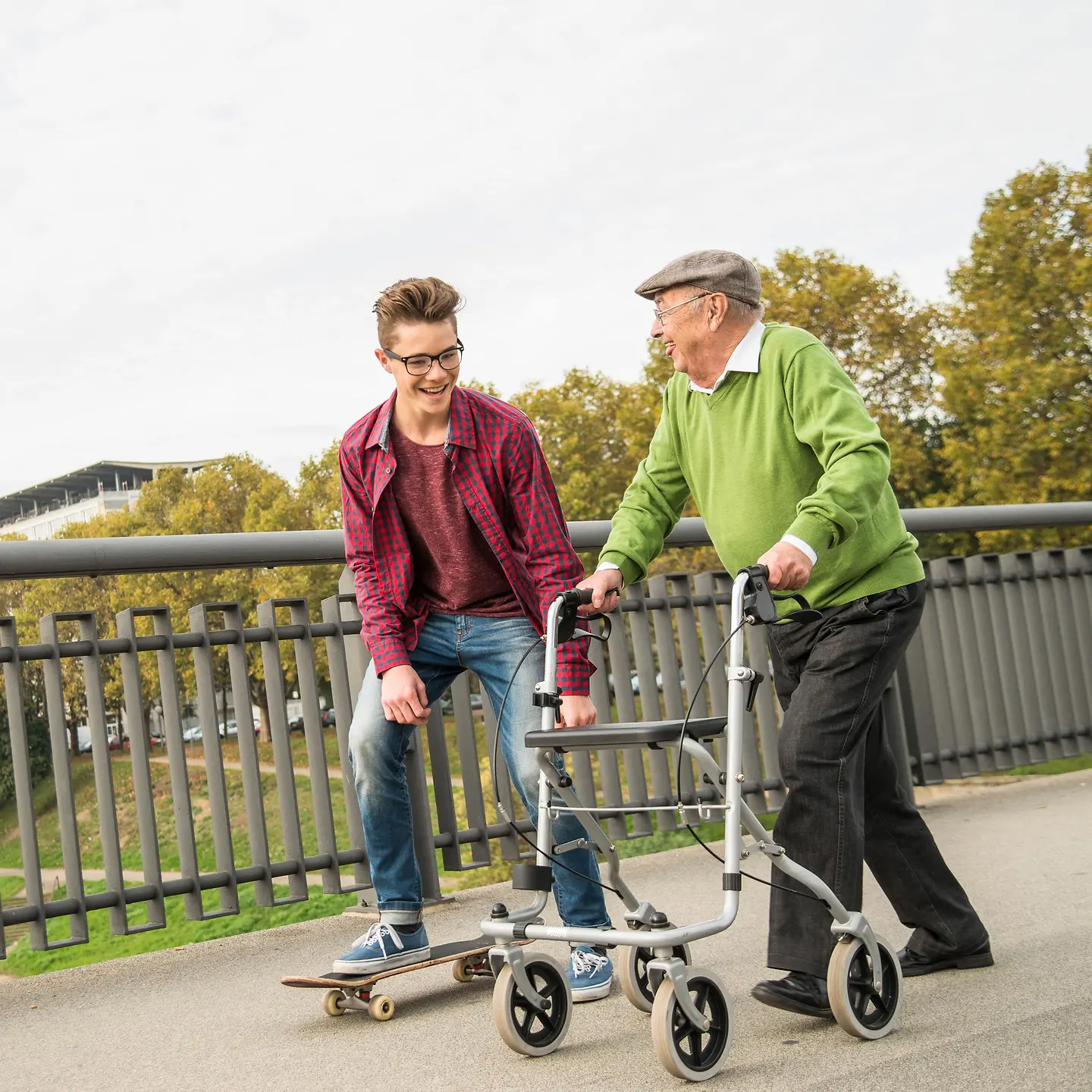 Ein älterer Mann mit Rollator und ein Junge mit Skateboard