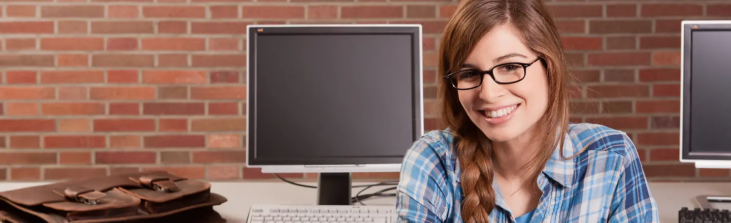 Eine Schülerin sitzt an einem Schreibtisch mit PC