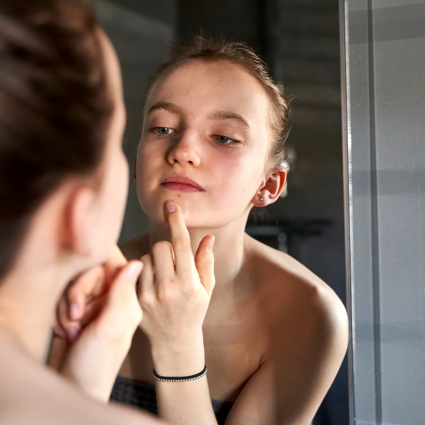 Eine Frau tastet ihr Gesicht im Spiegel ab