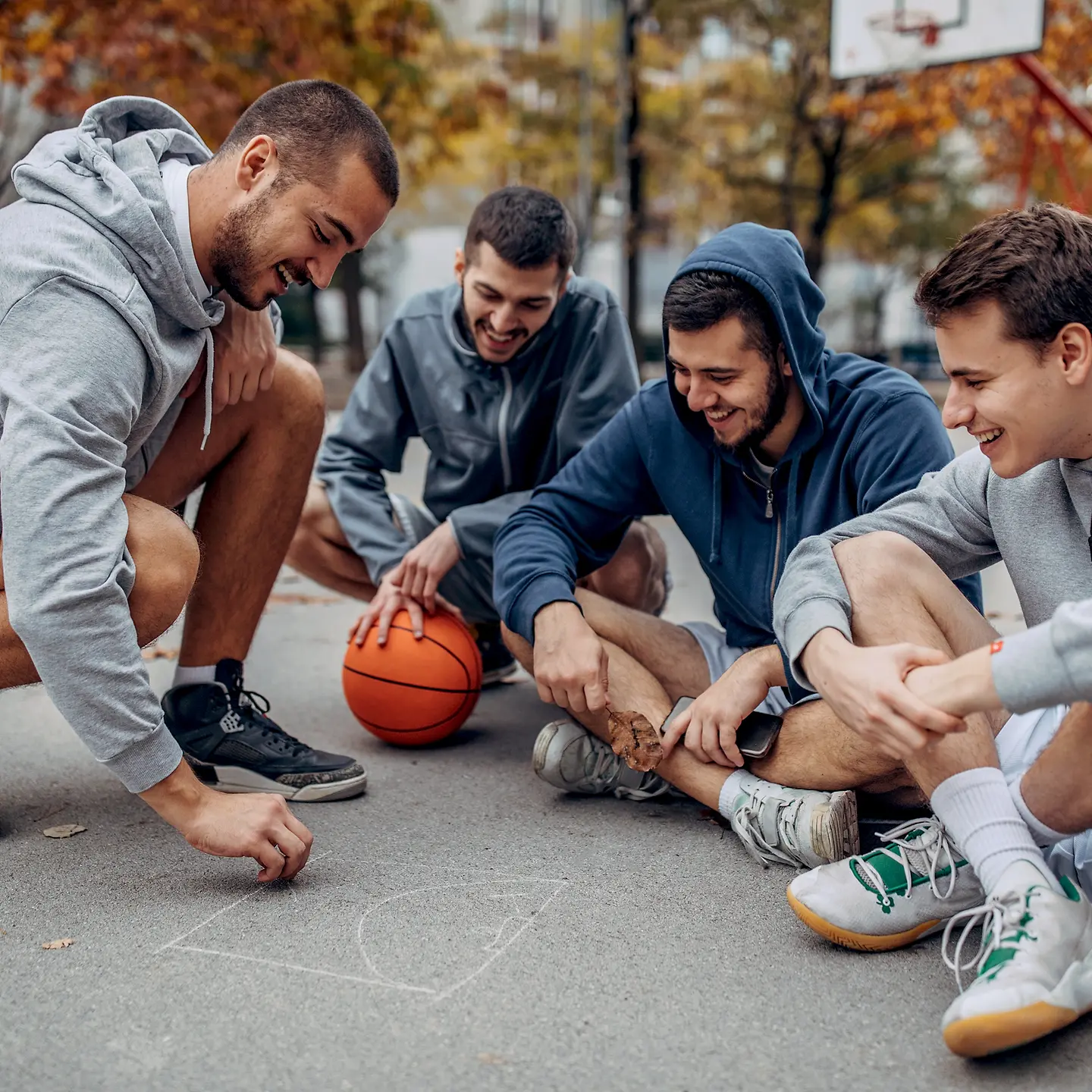 Eine Gruppe sitzt outdoor mit Basketball auf dem Boden