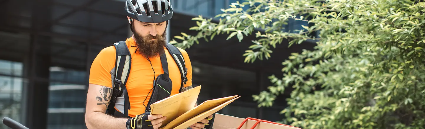 Ein Fahrradkurier mit Paketen und Briefen