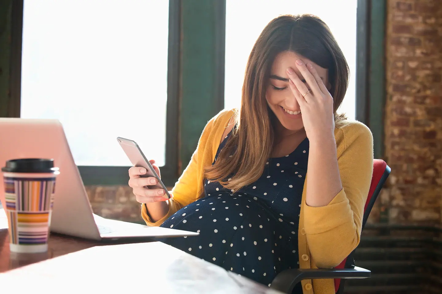 Schwangere Frau liest etwas Lustiges im Internet