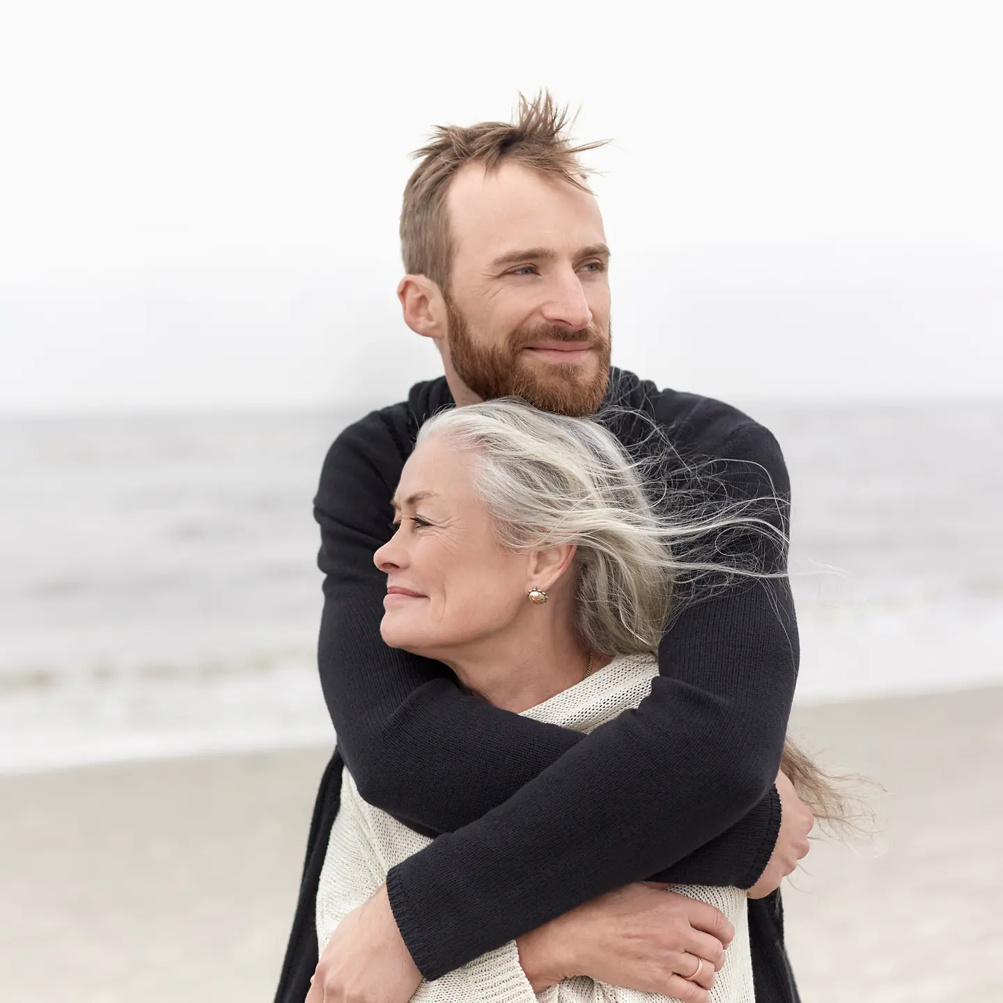 Ein Mann umarmt seine Mutter am Strand.