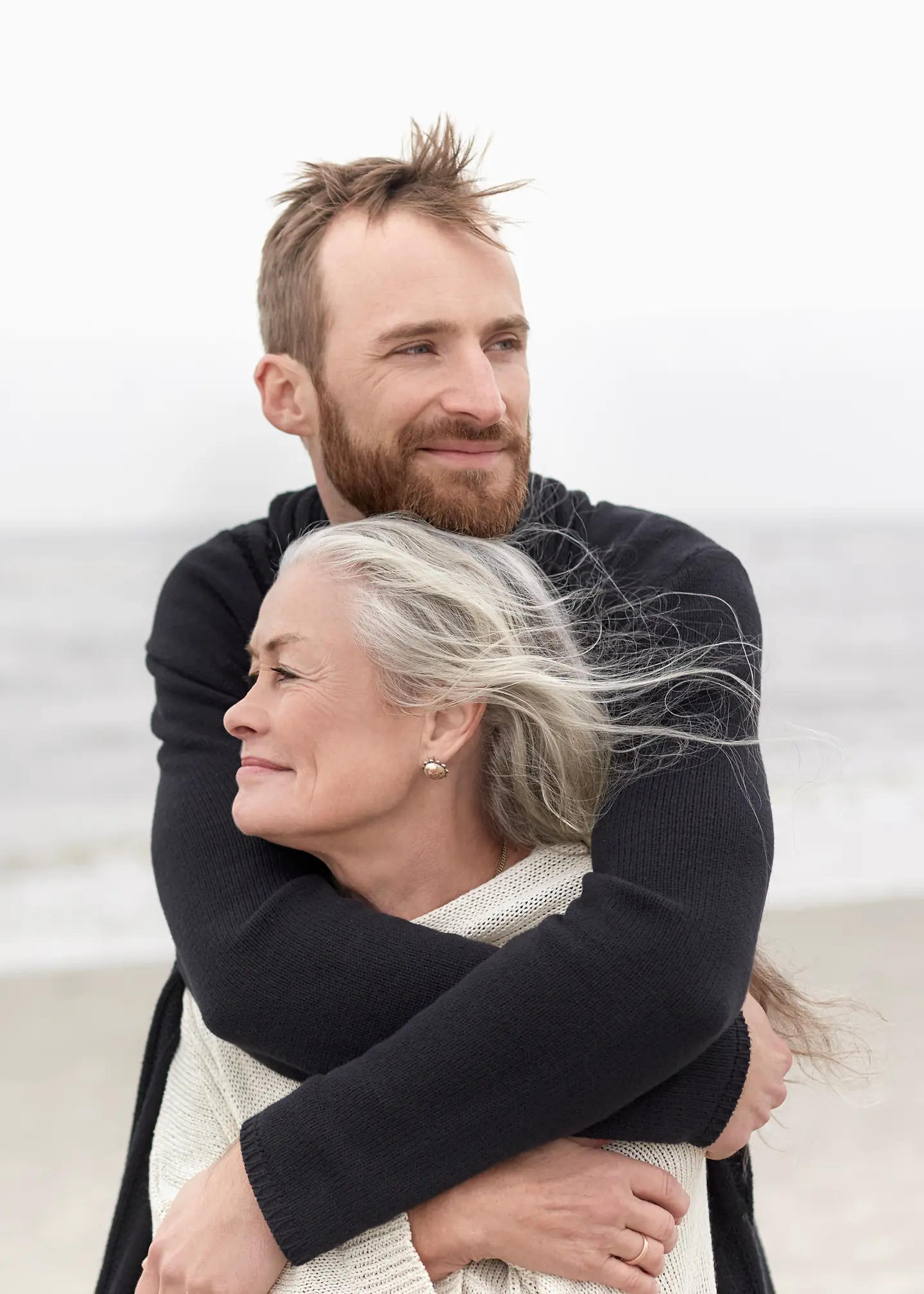 Ein Mann umarmt seine Mutter am Strand.