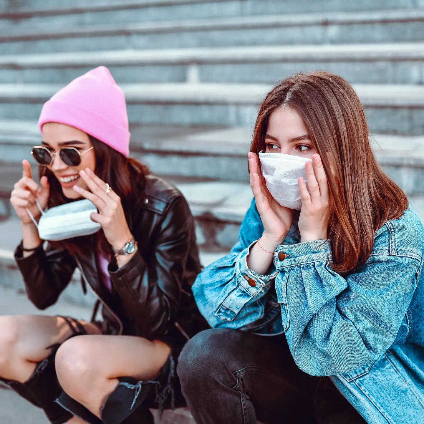 Zwei Jugendliche sitzen auf einer Treppe und tragen eine Mund-Nase-Schutzmaske