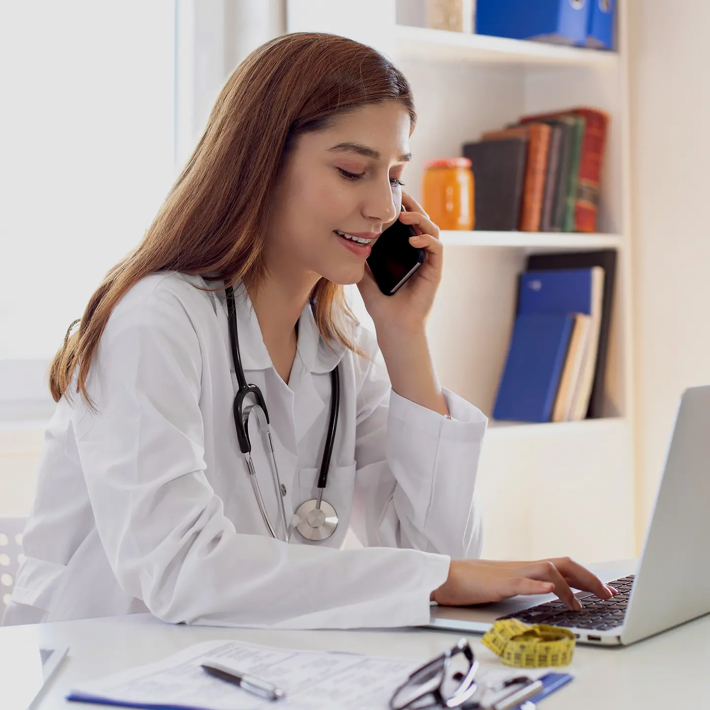 Ärztin am Rechner und Smartphone