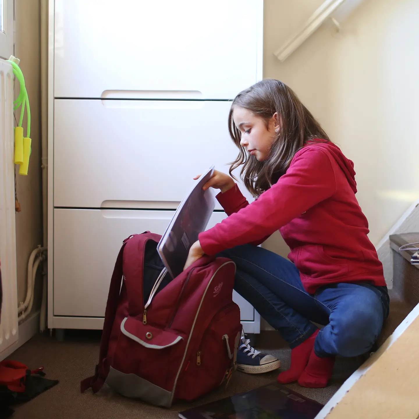 Ein Mädchen sitzt auf einer Treppe und packt ihren Schulrucksack
