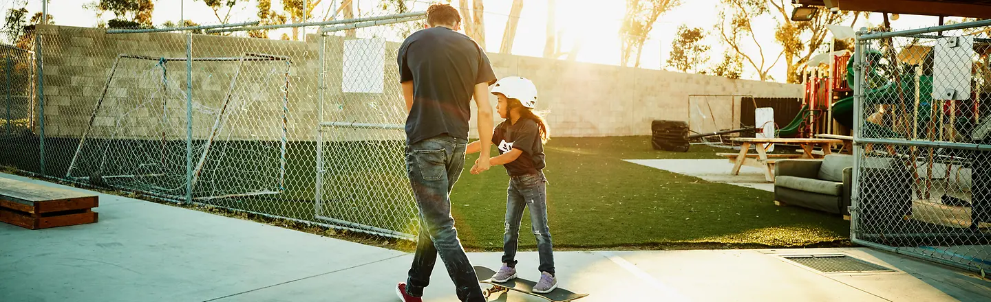 Ein junger Mann hilft einem Mädchen beim Skateboardfahren