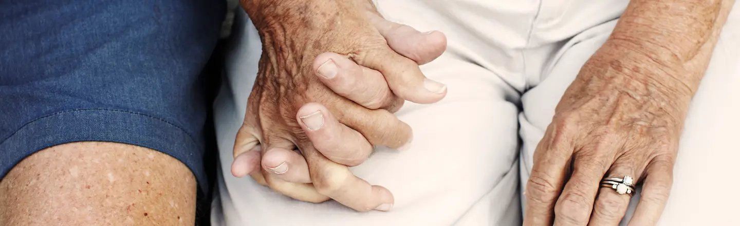 Zwei ältere Menschen haben die Hände ineinander verschränkt