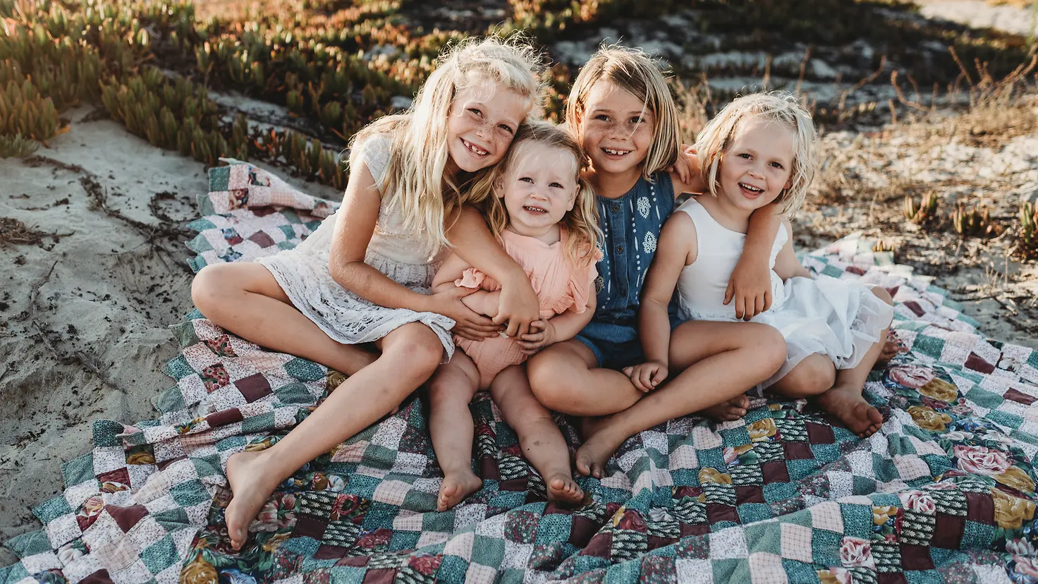 Vier kleine Mädchen sitzen auf einer Stranddüne