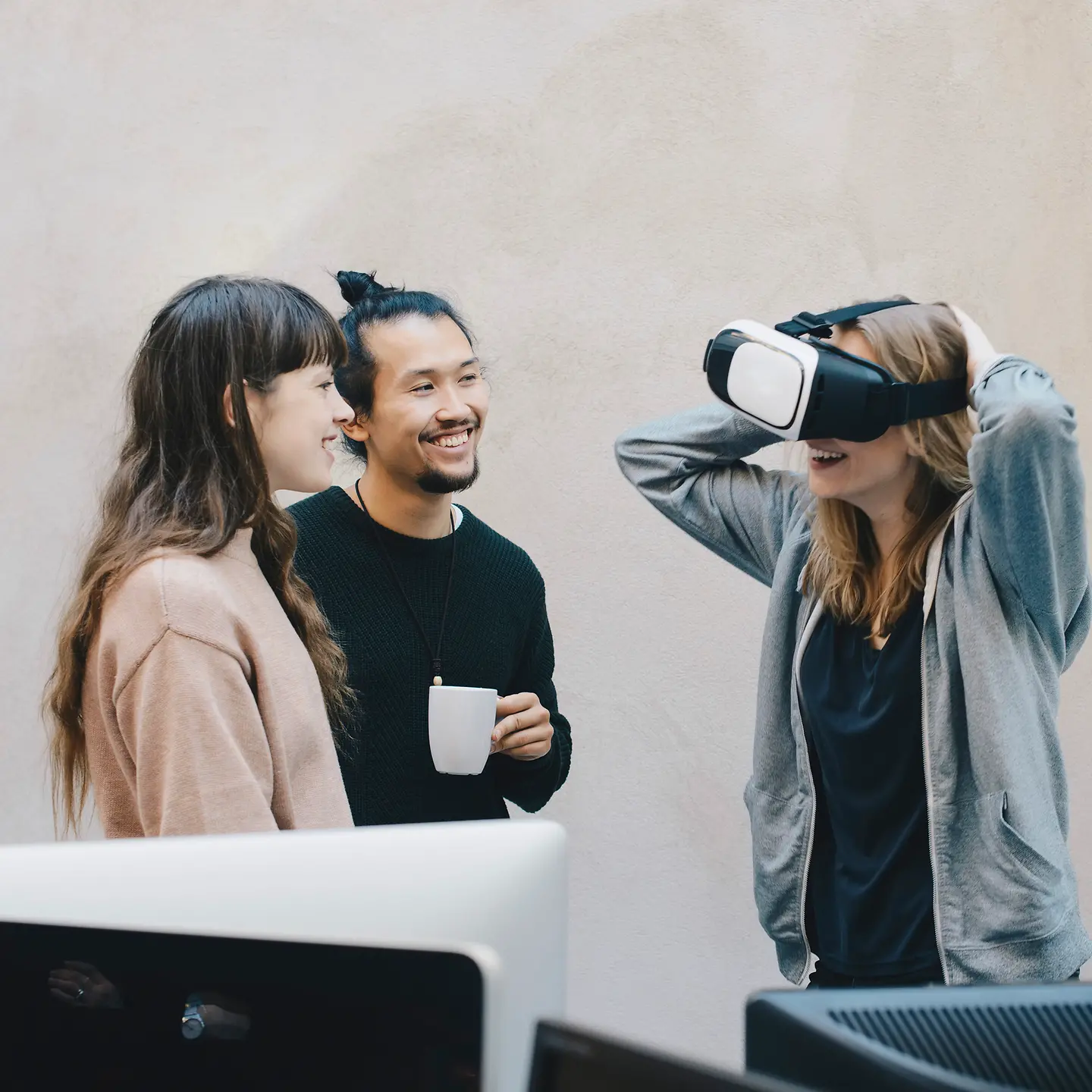 Eine Gruppe junger Leute steht gemeinsam vor Monitoren, eine Dame trägt eine Augmented Reality Brille